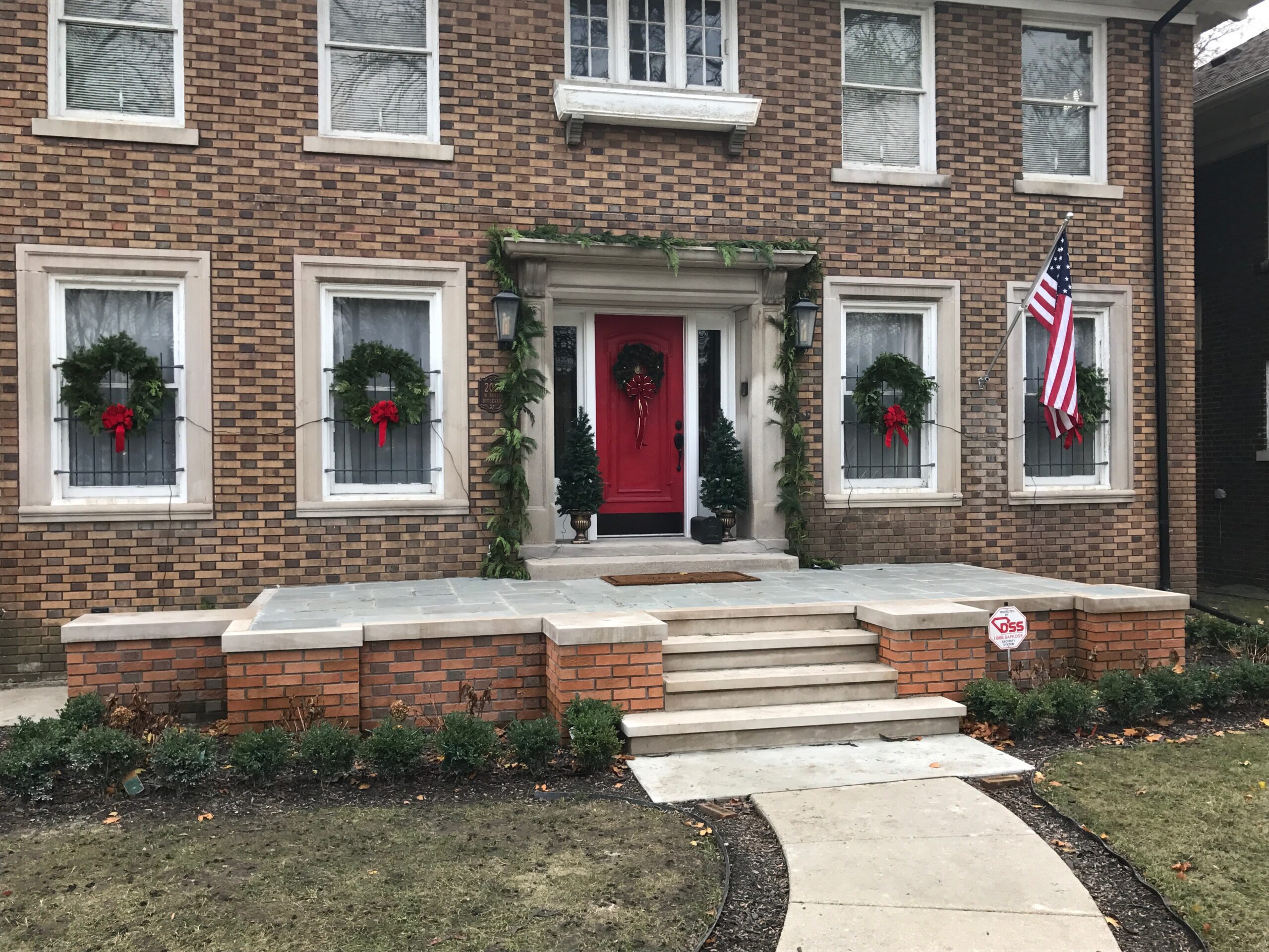 Two story brick house with American flag decorated for Christmas