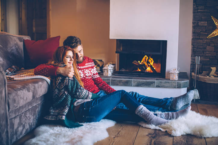 Man and woman cuddling in front of fireplace in winter