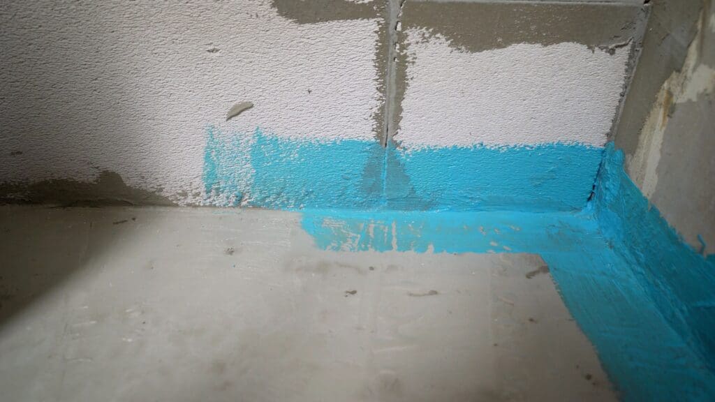 Blue waterproofing paint applied to a basement wall